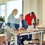 Office image with employees surround a desk reading about the Work Opportunity Tax Credit WOTC